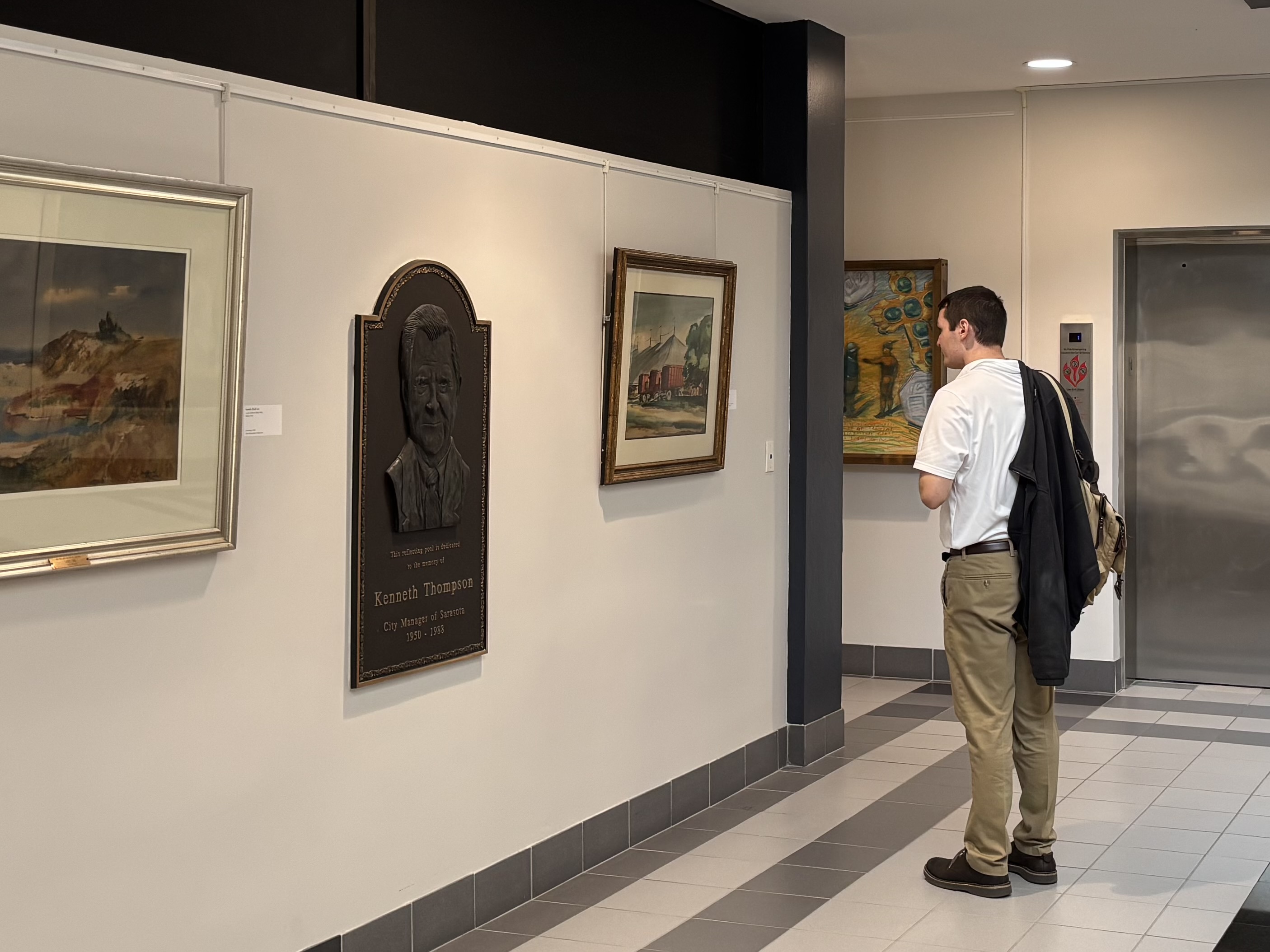 A person stands in front of one of several artworks in the 