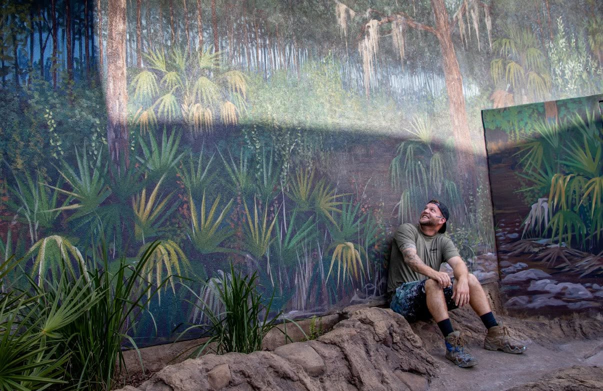 Artist Andrew Viera in front of a mural